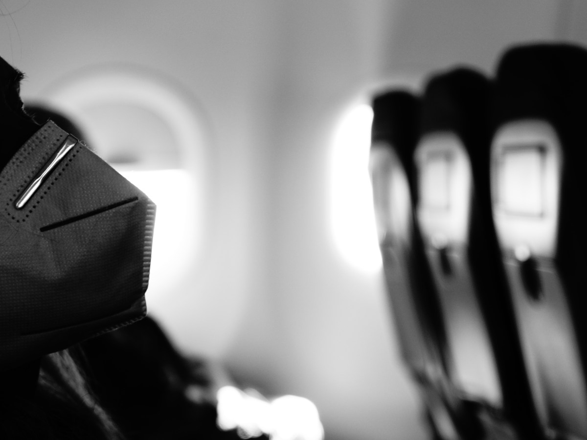 The problem with removing travel mask mandates | Person with mask on plane